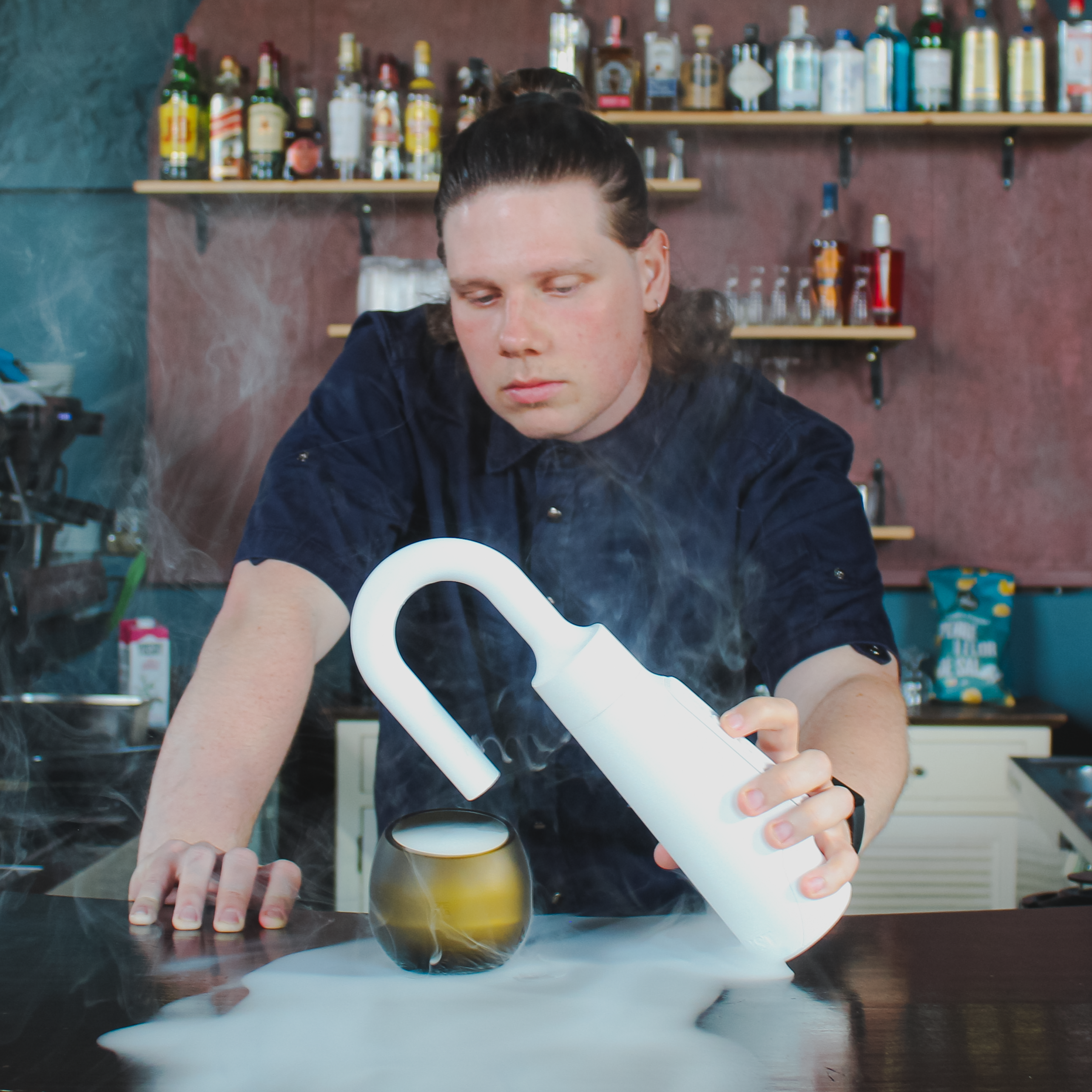 Bartender using MIST edible fog generator to aromatize a cocktail with cold aromatic mist