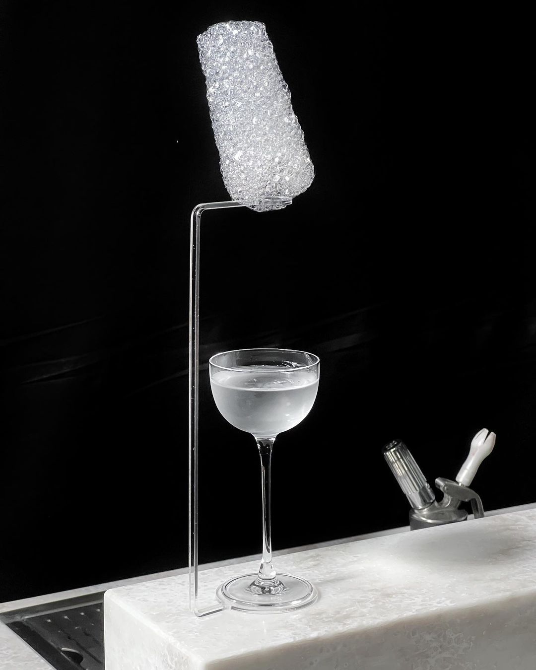 VOM edible cloud floating above a coupe cocktail glass — flying garnish for molecular mixology